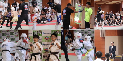 武道大会の集合写真。選手の演武や審判、観客が見守る場面を捉えた賑やかな様子。